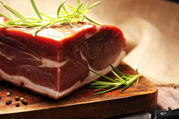 Italian prosciutto crudo or jamon with rosemary. Raw ham on wooden board