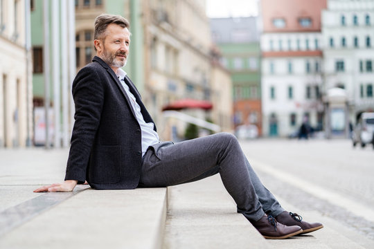 Germany, Zwickau, relaxed mature businessman sitting on steps outdoors