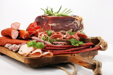 Food tray with delicious salami, pieces of sliced ham, sausages,salad and vegetable. Meat platter with selection