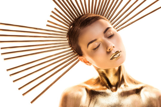 nude young woman painted in golden with accessory on head and closed eyes isolated on white