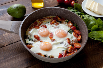 Keto breakfast: eggs, bacon, butter, tomatos,avocado, nutc, etc. on table. Flat lay. 