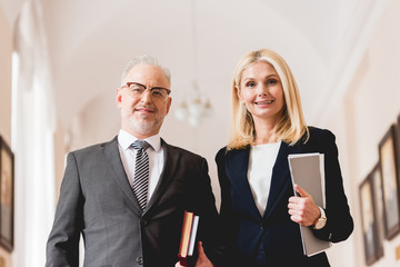 low angle view of cheerful teachers looking at camera while holding books