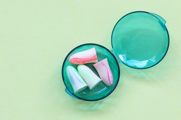 Earplugs in a box on the green background. Good sleep and noise protection concept.