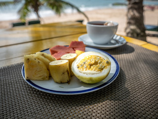 Fruit breakfast and cup of tea on the sunny beach. Travel cuisine.