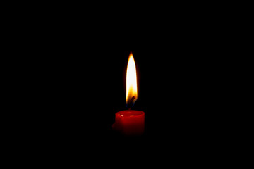Red candle isolated in a black background with no wind
