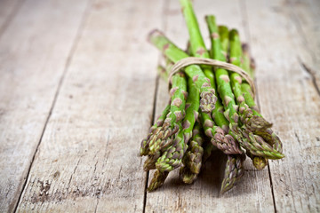 Bunch of fresh raw garden asparagus on rustic wooden table background. Green spring vegetables.