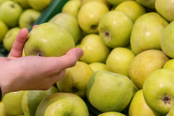 Women hand choosing apple at supermarket