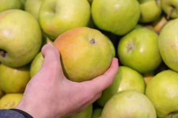 Women hand choosing apple at supermarket
