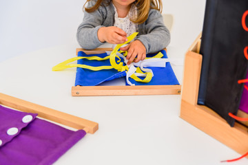 Girl practicing how to tie ties in a wooden frame.