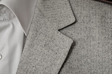  Light grey tweed or woolen jacket with a collar fragment.