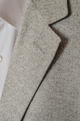  Light grey tweed or woolen jacket with a collar fragment.