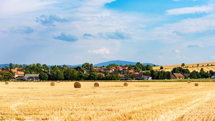 Fototapeta premium field with bales of hay in front of german village