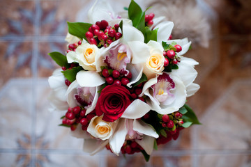 Exquisite bouquet of red and white roses with orchids, complemented by red hypericum berries