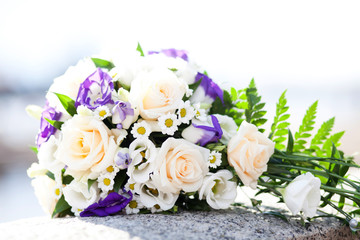 Rosebuds and eustoma in combination with a field chamomile in a refined wedding bouquet on a granite surface