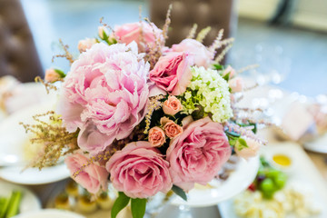 Bridal bouquet of pink roses and peonies on a blurred background window
