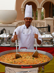 chef cooking spanish paella in outdoor area