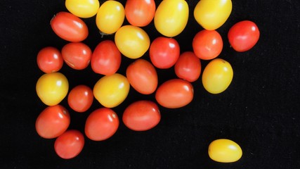 Tomates cherry rojos y amarillos sobre fondo negro