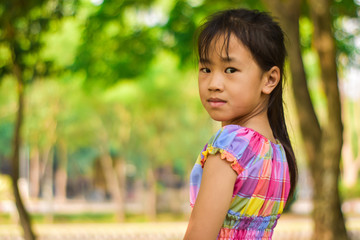Close-up portrait of beautiful little girl in a summer green park.
