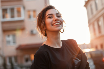 Young happy woman with a beautiful smile in a stylish T-shirt in a coat is standing and enjoying...