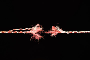 Tearing the red rope in the middle of the frame on black background