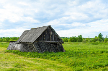 Obraz premium An old rickety barn that's about to fall apart stands in the middle of the field