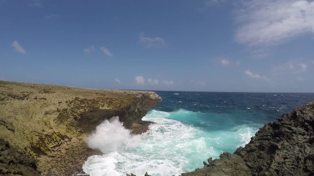 A blowhole spilling sea water due to the rough surf and waves at a cliff of the east coast of tropical Bonaire island in the caribbean