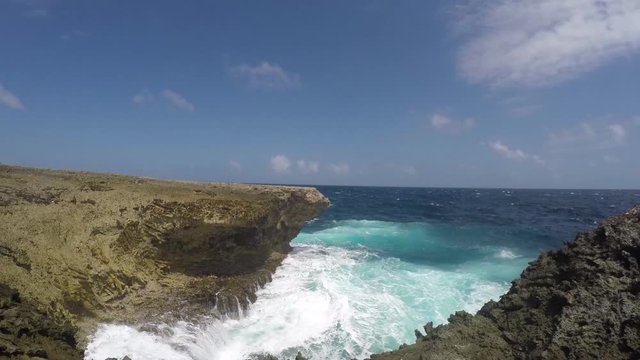 A blowhole spilling sea water due to the rough surf and waves at a cliff of the east coast of tropical Bonaire island in the caribbean