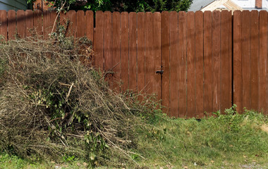 Piled yard cleanup debris against left side of brown wood fence.