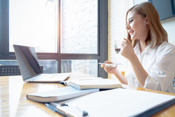 young businesswoman working with mobile phone laptop and holding coffee cup in office, business concept