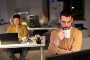 business, overwork and people concept - happy male office worker drinking coffee