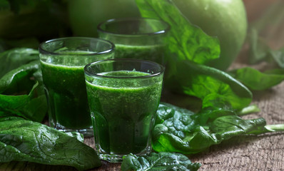 Green spinach detox smoothies with apples and lemon in glasses, selective focus