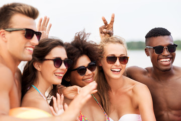 friendship, summer holidays and people concept - happy smiling friends in sunglasses on beach