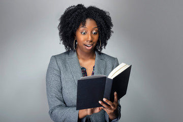 Black female author posing with a book in a studio for a portrait.  She looks like a teacher or a...