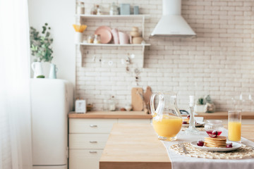 served table with pancakes and orange juice in kitchen