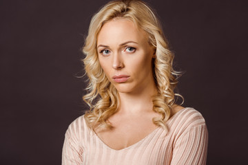 upset blonde woman looking at camera isolated on black