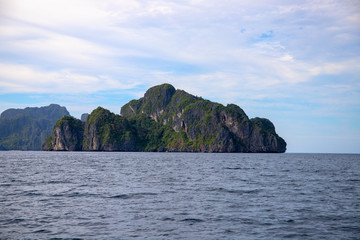 Fototapeta premium Tropical island in still sea. Black mountain sunny landscape. Philippines island hopping banner template.