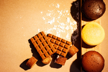 Cheese cakes, chocolate, sugar cane and crackers with wood on paper. Sweetmeat concept. Original, choco and macha flavor.