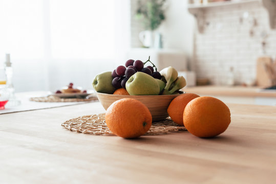 Bowl With Apples, Bananas, Grapes And Oranges On Table