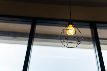 light bulb in black steel cage hang on ceiling in coffee shop, Fashion and lamp in modern style.