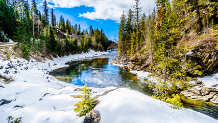 Water of the Murtle River tumbles over the edge of the partly frozen Mushbowl Falls in the Cariboo Mountains of Wells Gray Provincial Park, British Columbia, Canada