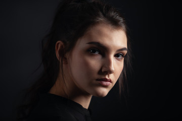 Fototapeta premium Dramatic portrait of a beautiful girl on a dark background