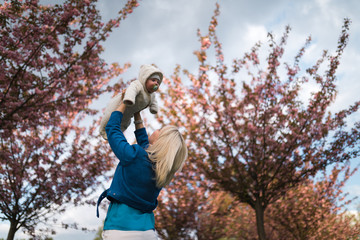 Young mother woman enjoying free time with her baby boy child - Caucasian white child with a parent's hand visible - Dressed in white overall with hearts, mom in blue