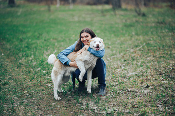 Young woman play with husky dog for a walk in spring forest. laughing having fun, happy with pet