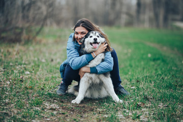 Young woman play with husky dog for a walk in spring forest. laughing having fun, happy with pet