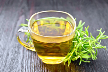 Tea of rosemary in cup on dark wooden board
