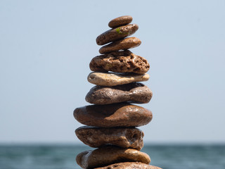 Fototapeta na wymiar sea ​​stones to each other in the form of a tower against the background of the sea and sky