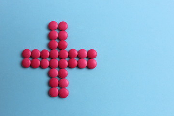 Pink pills lined up with a plus sign