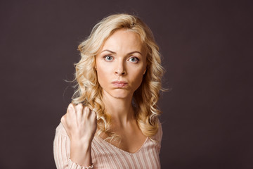 angry blonde woman looking at camera and showing fist isolated on black