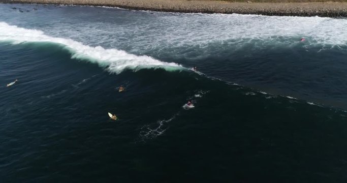 Young surfer riding wave from behind the line up in tropical. Aerial view of surf break summer activity. 