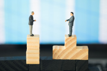 Two miniature businessmen shaking hands